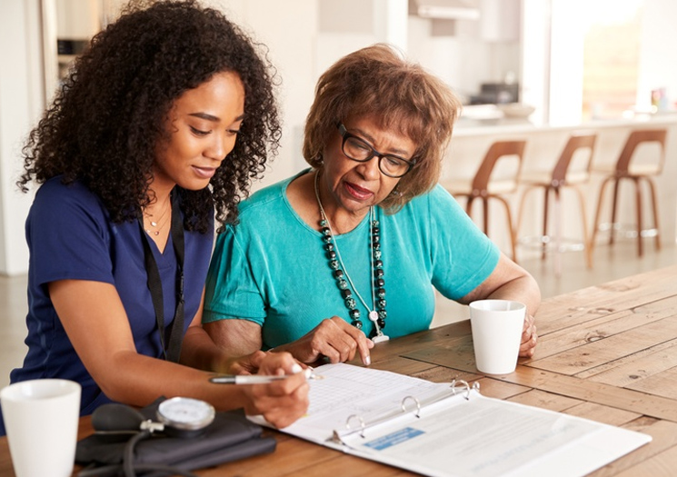 Nurse helping an older woman write