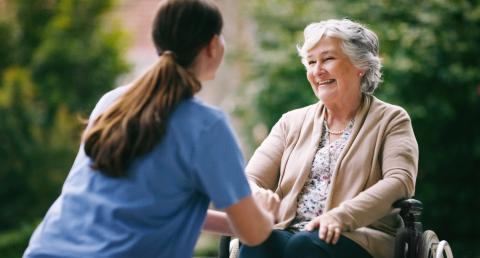 Elderly woman with professional caregiver in nursing home garden